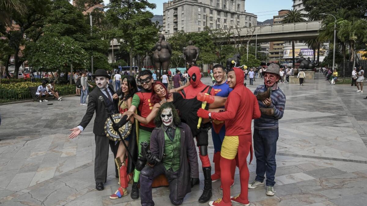 Venezuelan migrant Johnny Tales (C-bottom), who makes a living imitating the comicbook and film character "The Joker", pose with fellow compatriots also fancy dressed as comic and film industry characters in downtown Medellin, on October 29, 2019. JOAQUIN SARMIENTO / AFP