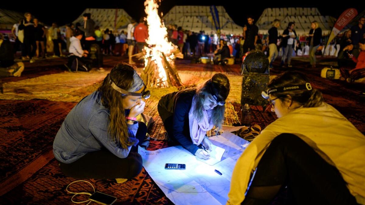 Women read and look at their map at the resting camp as they take part in the desert trek "Rose Trip Maroc", on October 31, 2019 in the erg Chebbi near Merzouga. The Rose Trip Maroc is a female-oriented trek where teams of three must travel through the southern Moroccan Sahara desert with a compass, a map and a topographical reporter. JEAN-PHILIPPE KSIAZEK / AFP
