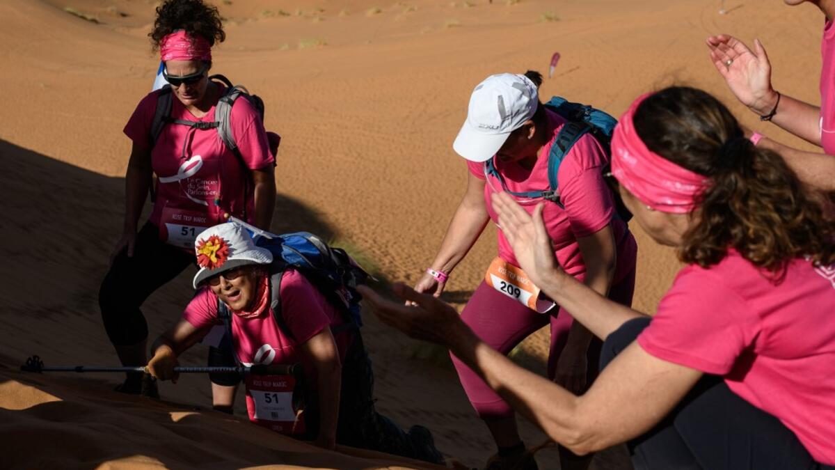 Women encourage each other as they take part in the desert trek "Rose Trip Maroc", on November 4, 2019 in the erg Chebbi near Merzouga. The Rose Trip Maroc is a female-oriented trek where teams of three must travel through the southern Moroccan Sahara desert with a compass, a map and a topographical reporter. JEAN-PHILIPPE KSIAZEK / AFP