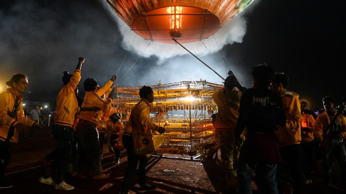 This picture taken on November 4, 2019 shows participants releasing a hot-air balloon attached with fireworks during the Tazaungdaing Lighting Festival at Taunggyi in Myanmar's northeastern Shan State. Brightly coloured balloons with hundreds of homemade fireworks woven into their frames are sent soaring into the night sky, showering down cascades of sparks onto adoring crowds in the annual Taunggyi fire balloon festival. Ye Aung THU / AFP