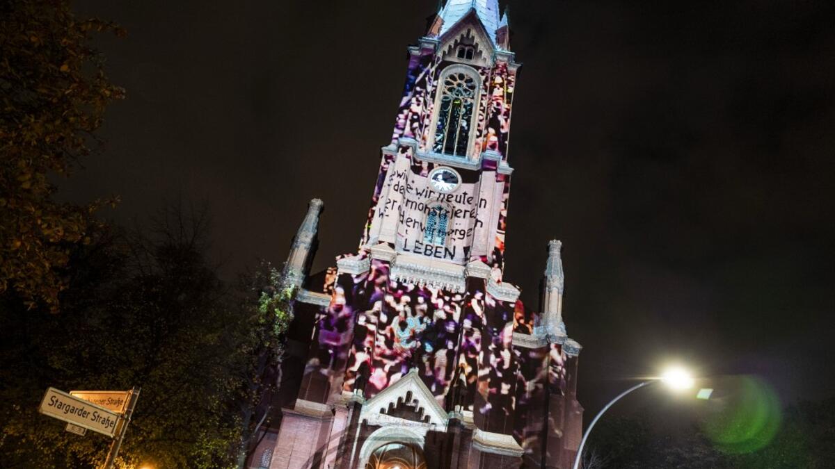 Photos showing mass demonstrations in the former East Germany in 1989 are projected on to the Gethsemane Church as part of the festival week to celebrate the 30th anniversary of the November 9,1989 fall of the Berlin Wall, in Berlin on November 5, 2019. John MACDOUGALL / AFP