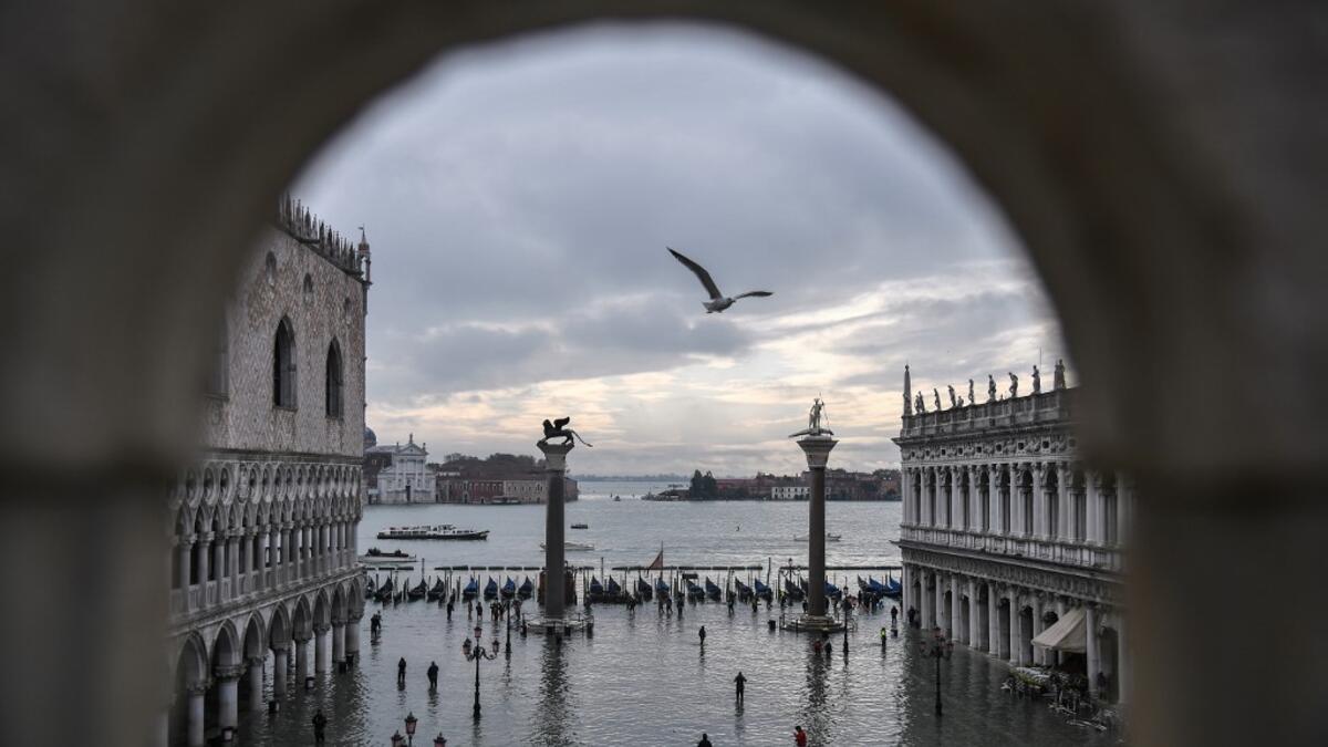 A general view shows the Doge's Palace (L) overlooking the flooded St. Mark's Square, the Lion of St. Mark winged bronze statue (Rear L), gondolas and the Venetian lagoon in the distance after an exceptional overnight "Alta Acqua" high tide water level, on November 13, 2019 in Venice. Venice was hit by the highest tide in more than 50 years late November 12, with tourists wading through flooded streets to seek shelter as a fierce wind whipped up waves in St. Mark's Square. Marco Bertorello / AFP