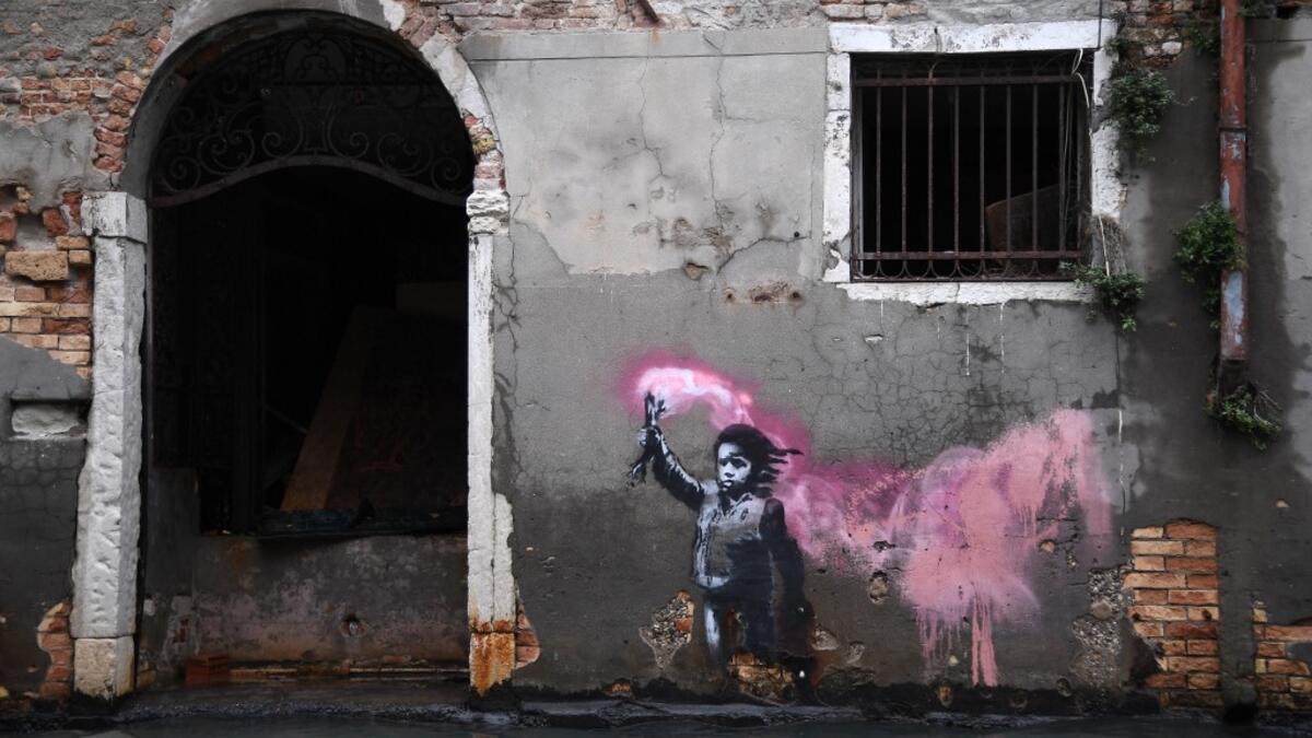 The artwork by street artist Banksy, that portrays a migrant child wearing a lifejacket and holding a neon pink flare, is pictured after an exceptional overnight "Alta Acqua" high tide water level, on November 13, 2019 in Venice. Venice was hit by the highest tide in more than 50 years late November 12, with tourists wading through flooded streets to seek shelter as a fierce wind whipped up waves in St. Mark's Square. Marco Bertorello / AFP