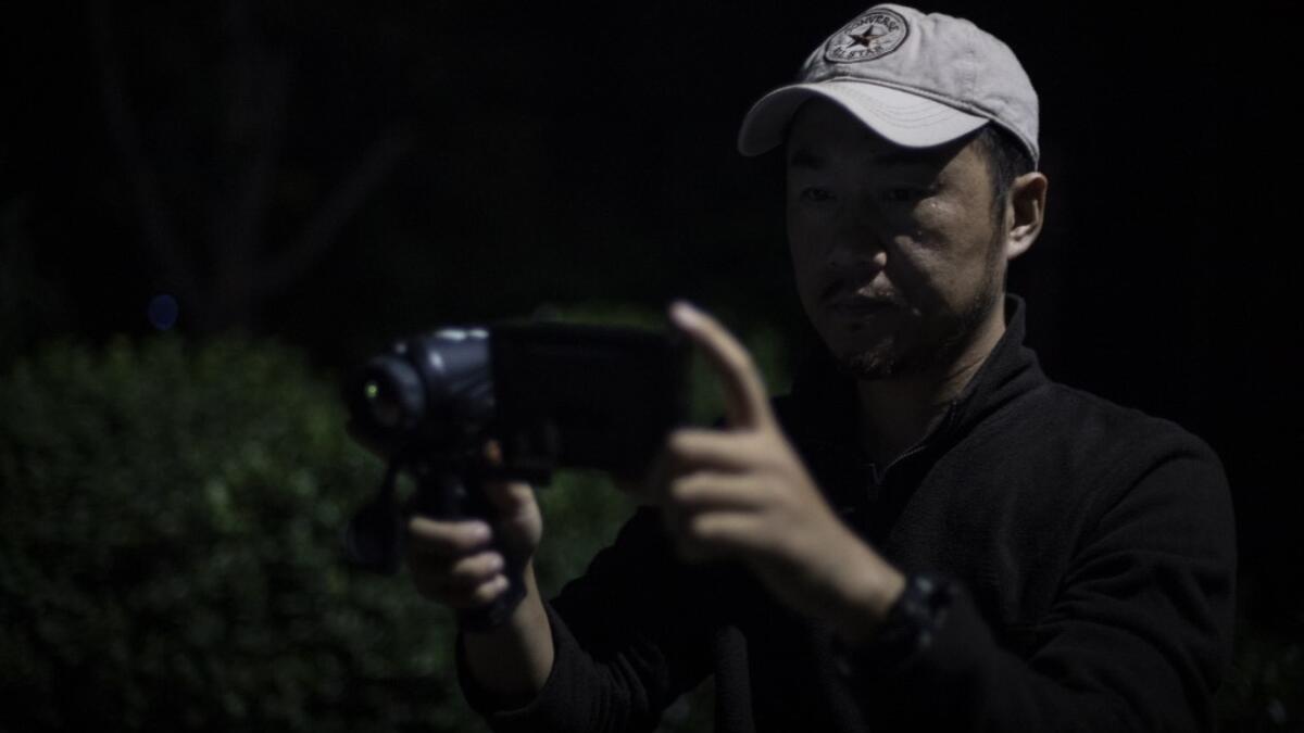 This photo taken on October 23, 2019 shows pet detective Sun Jinrong using a night vision camera as he searches for a missing cat in a residential compound in Beijing. Private sleuth Sun Jinrong brings heat detectors, tiny surveillance cameras, and a blowdart loaded with a tranquiliser to his search for one desperate client's missing loved one: A cat named Duoduo.  NOEL CELIS / AFP