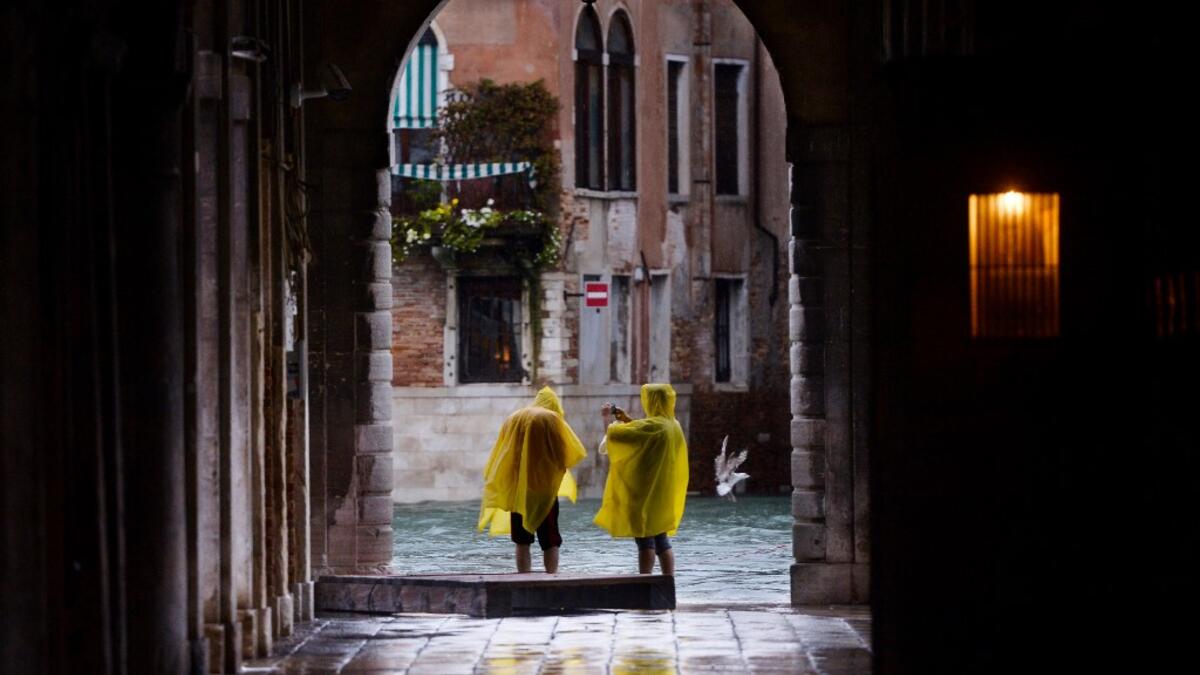 People take pictures in a street near the Rialto Bridge, on November 15, 2019 in Venice, two days after the city suffered its highest tide in 50 years. Flood-hit Venice was bracing for another exceptional high tide on November 15, as Italy declared a state of emergency for the UNESCO city where perilous deluges have caused millions of euros worth of damage. Filippo MONTEFORTE / AFP