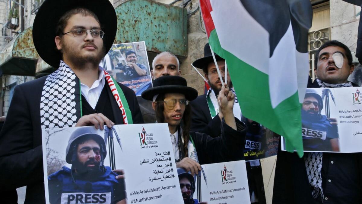 Palestinian demonstrators and religious Jewish men belonging to Neturei Karta, a small faction of anti-Zionist ultra-Orthodox Jews who oppose Israel's existence, take part in a demonstration in support of Muath Amarneh, a photographer who was hit in the eye last week during clashes between Israeli border police and Palestinian demonstrators in the village of Surif, in front an Israeli checkpoint in the divided Palestinian city of Hebron on November 18, 2019. HAZEM BADER / AFP