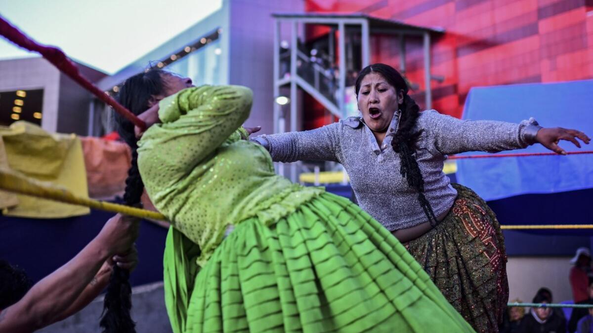 Bolivian wrestler Ana Luisa Yujra (R), aka "Jhenifer Two Faces" and Lidia Flores, aka "Dina, The Queen of the Ring", both members of the Fighting Cholitas, fight at Sharks of the Ring wrestling club in El Alto, Bolivia, on November 24, 2019. After a fortnight hiatus due to anti-government protests and blockades, the Fighting Cholitas are back in the ring. The unrest was triggered by the disputed October 20 election, which Evo Morales claimed to have won and opposition groups said was rigged. Ronaldo SCHEMID