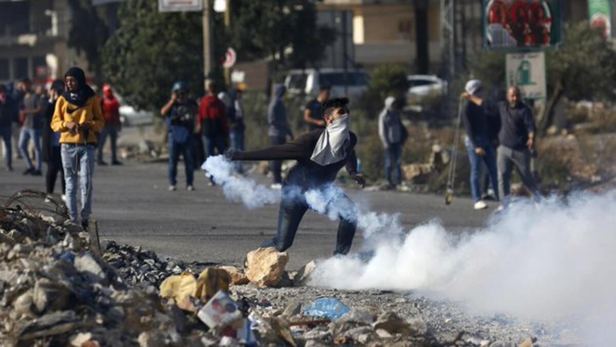 A Palestinian youth uses a slingshot to hurl a stone towards Israeli security forces on November 26, 2019 during clashes in the West Bank city of Hebron as Palestinians stage a "day of rage" against a recent US decision to no longer consider settlements in the West Bank illegal (Twitter)