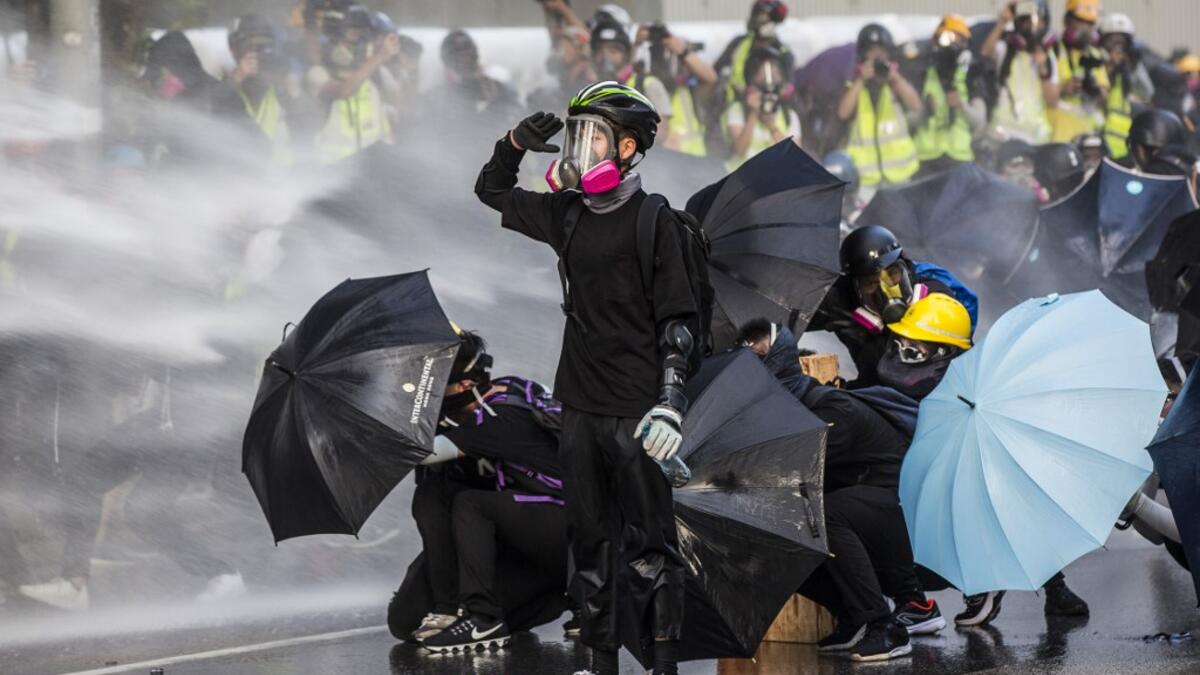AFP PICTURES OF THE YEAR 2019 - Pro-democracy protesters react as police fire water cannons outside the government headquarters in Hong Kong on September 15, 2019. Hong Kong riot police fired tear gas and water cannons on September 15 at hardcore pro-democracy protesters hurling rocks and petrol bombs, in a return to the political chaos plaguing the city. Isaac LAWRENCE / AFP