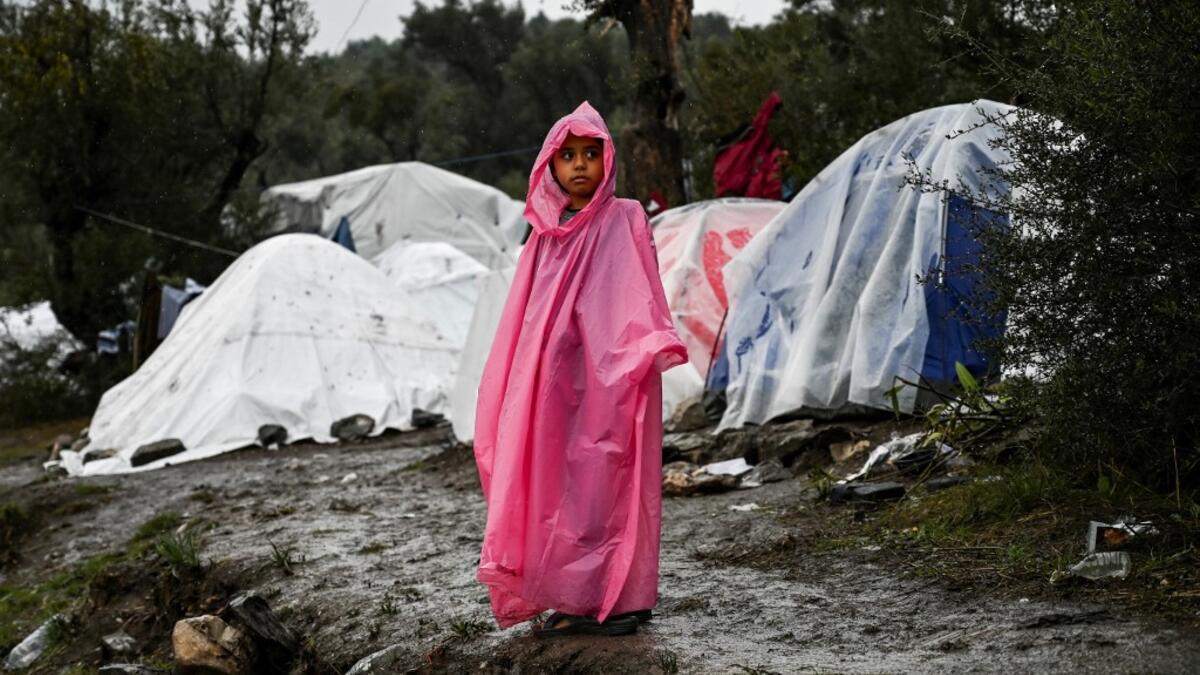 A young girl stands under the rain outside the refugee camp of Moria, on the island of Lesbos on November 26, 2019. Conditions remain difficult in the overcrowded Moria camp in Greece with winter fast approaching. The government announced on November 20it will shut down the three largest of its overcrowded migrant camps on islands facing Turkey, and replace them with new closed facilities with much larger capacity. ARIS MESSINIS / AFP