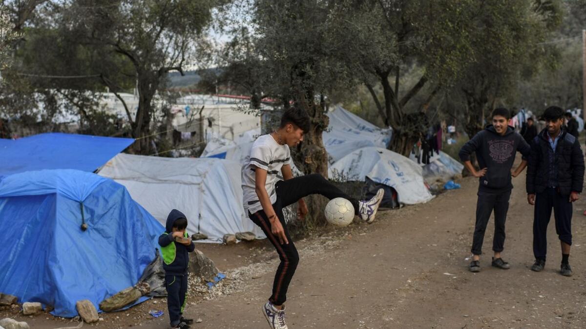 Children play with a ball at a makeshift camp outside the overcrowded Moria camp near the capital Mytilene in the island of Lesbos on November 28, 2019. Conditions remain difficult in the overcrowded camp in Greece with winter fast approaching. ARIS MESSINIS / AFP