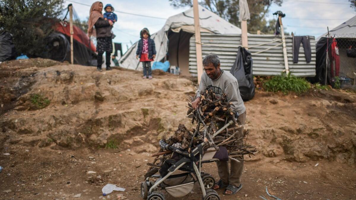 A man unloads firewoods from a baby troller at a makeshift camp next to the camp of Moria in the island of Lesbos on November 30, 2019. Conditions remain difficult in the overcrowded camp counting over 18.000 people with winter fast approaching. ARIS MESSINIS / AFP