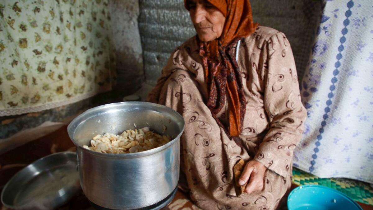 Umm Khaled cooks mushrooms in a pot in a camp in a town called Haarem in the northwestern province of Idlib on November 29, 2019. Aaref WATAD / AFP