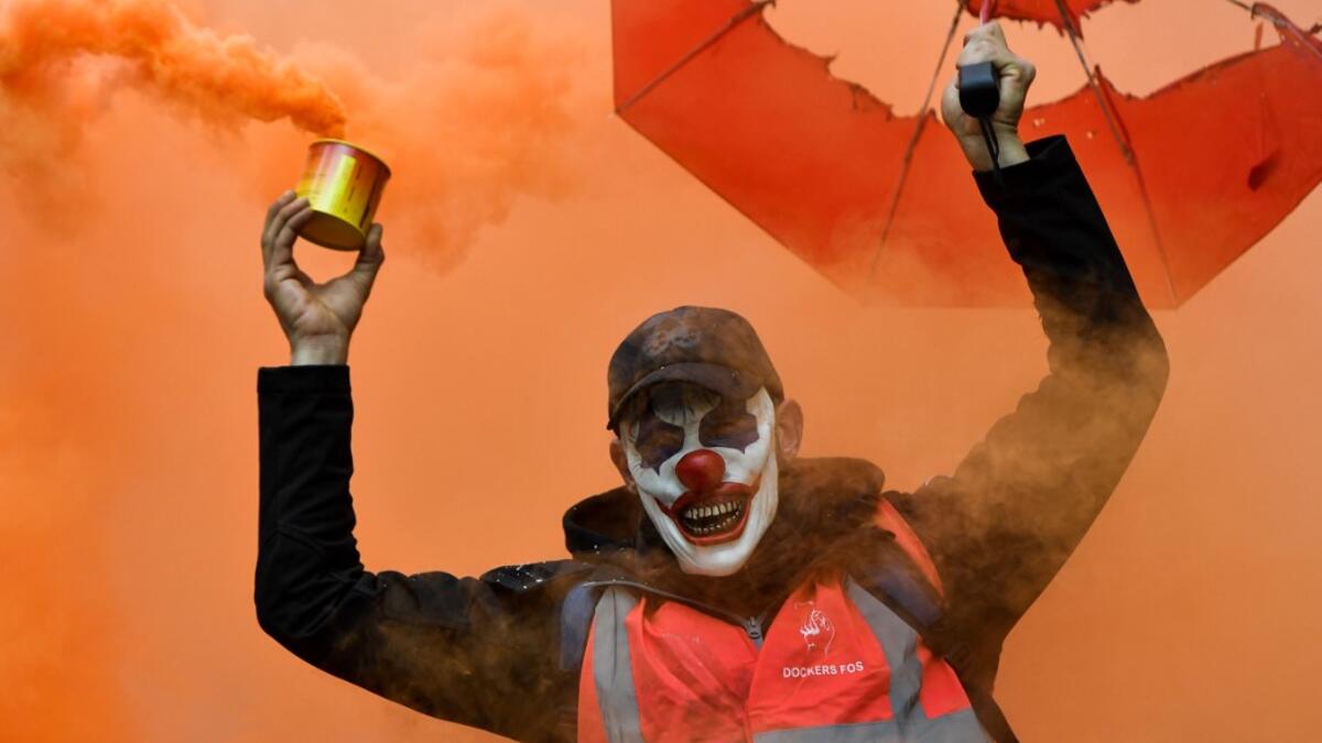 A man wearing the DC comic Joker character's mask and waving a smoke bomb takes part in a demonstration to protest against the pension overhauls, in Marseille, southern France, on December 5, 2019 as part of a national general strike. CLEMENT MAHOUDEAU / AFP
