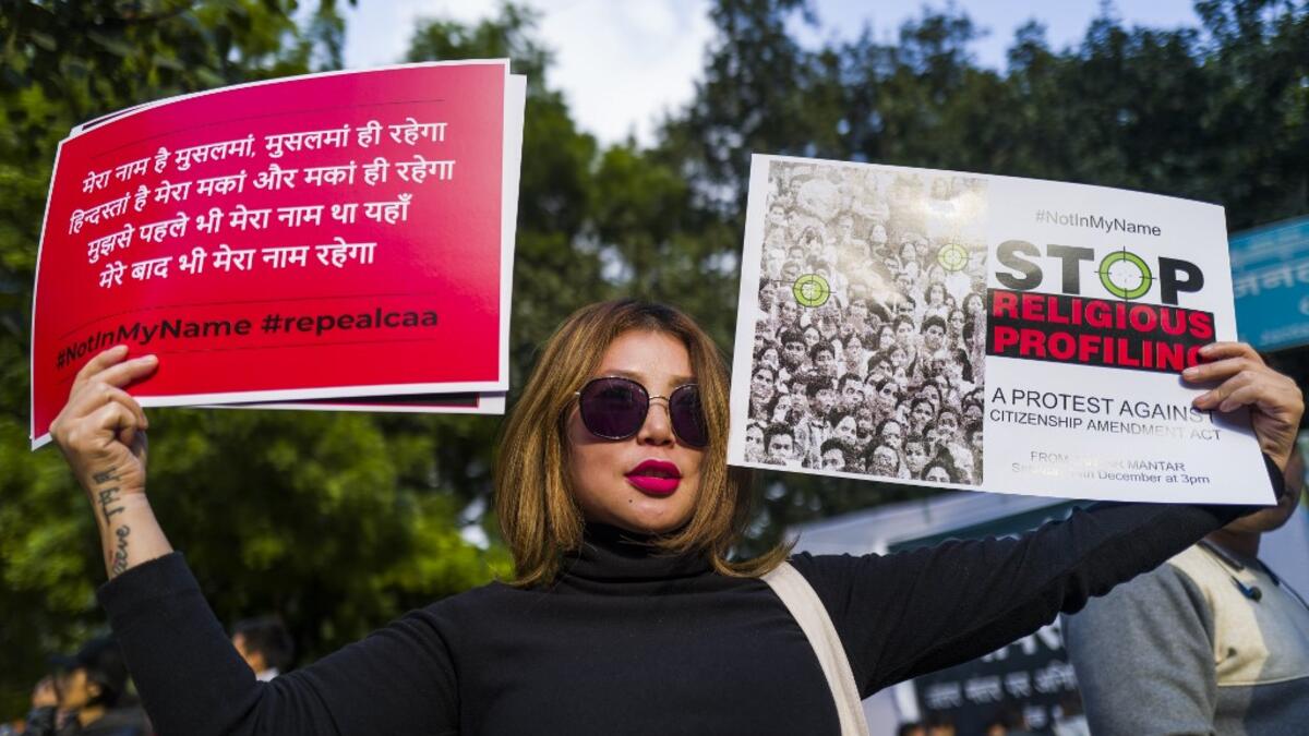 A protester displays placards during a demonstration against the Indian government's Citizenship Amendment Bill in New Delhi on December 14, 2019. Protests against a divisive new citizenship law raged on December 14 as Washington and London issued travel warnings for northeast India following days of violent clashes that have killed two people so far. Jewel SAMAD / AFP