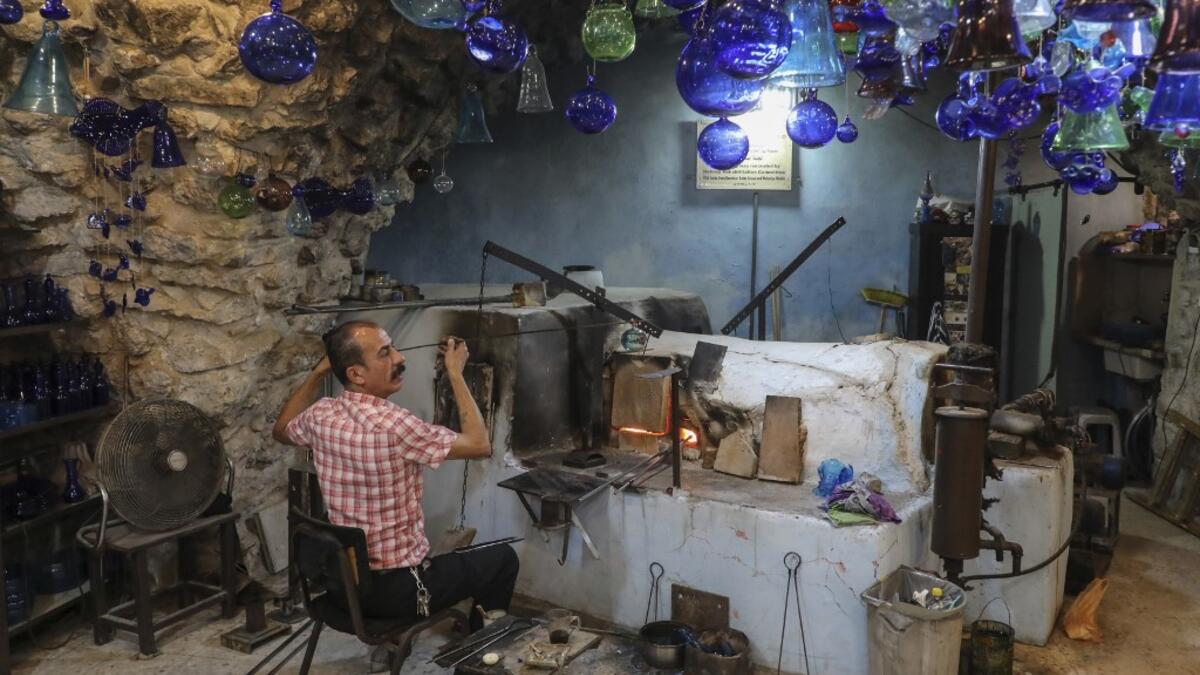 A Palestinian craftsman shapes molten glass into Christmas ornaments at his workshop in the southern West Bank city of Hebron, on December 15, 2019. HAZEM BADER / AFP