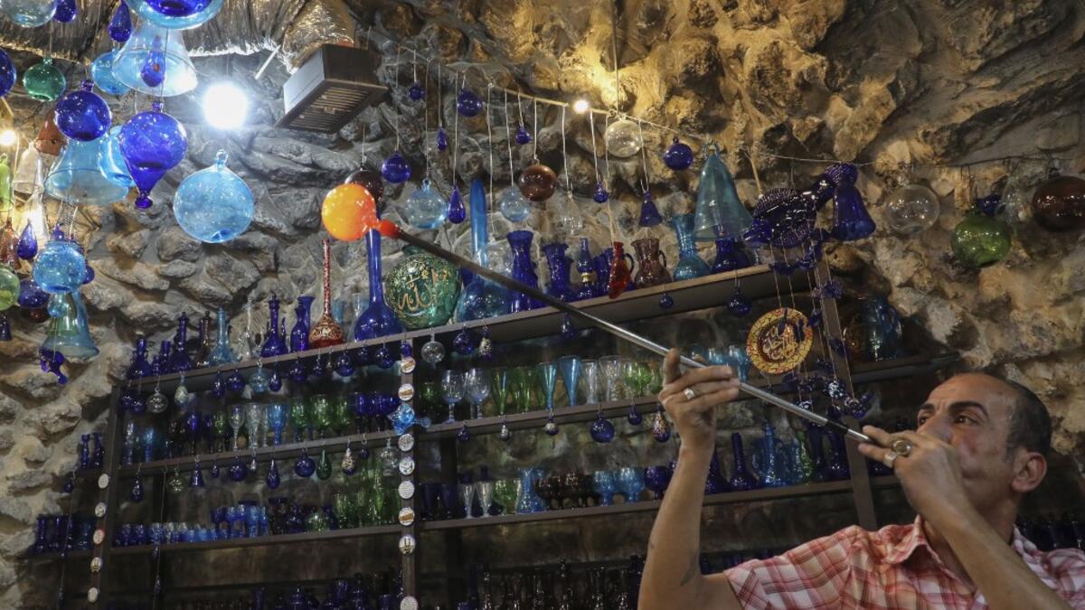 A Palestinian man blows molten glass into a Christmas ornament at his glass factory in the southern West Bank city of Hebron, on December 15, 2019. HAZEM BADER / AFP