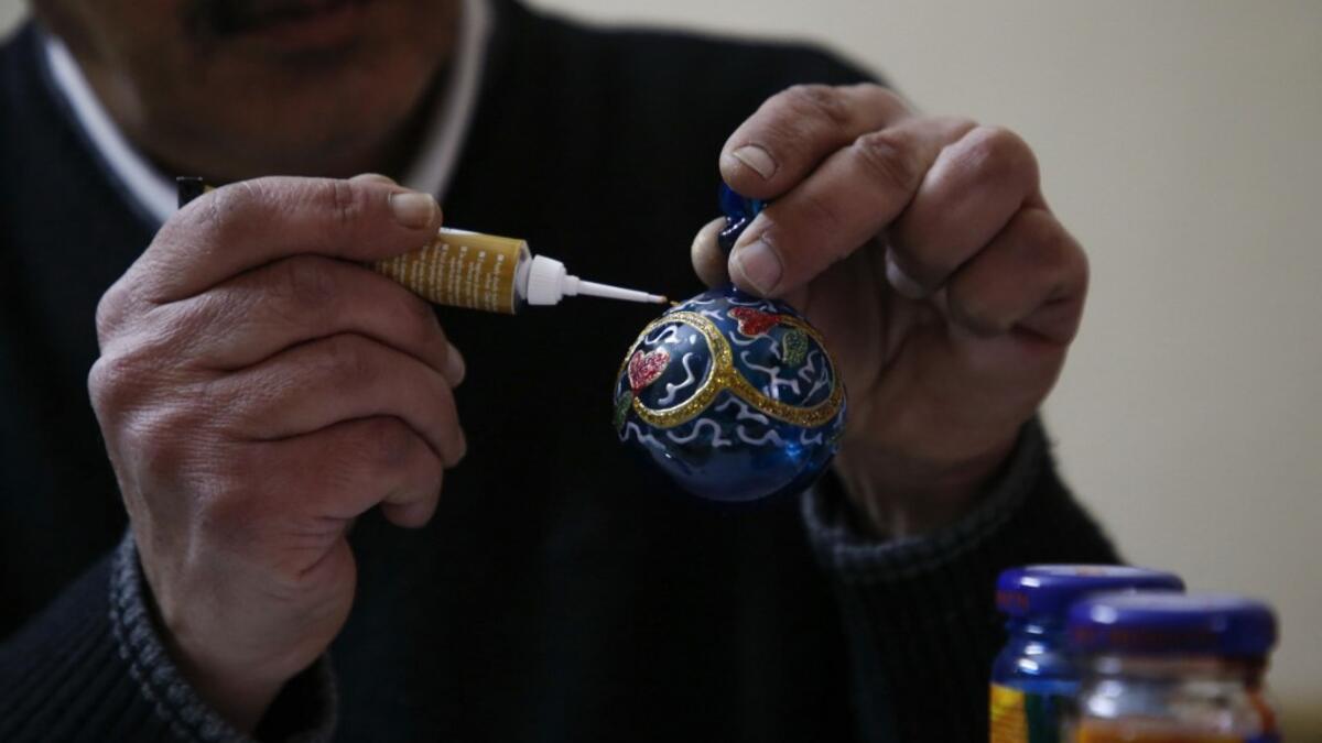 A Palestinian craftsman decorates a glass Christmas ornament at a workshop in the southern West Bank city of Hebron, on December 15, 2019. HAZEM BADER / AFP