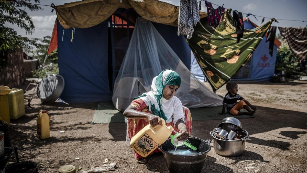 A displaced woman washes some dishes and utensils in front of her tent at a displacement camp in Beledweyne, Somalia, on December 14, 2019. The rains have inundated big areas surrounding Beledweyne area forcing thousands of people to leave their houses and look for humanitarian assistance while living in displacement camps. Due to climate change and human activities, cycles of floods and droughts have become more recurrent and completely unpredictable in Somalia exposing hundreds of thousands of people ever