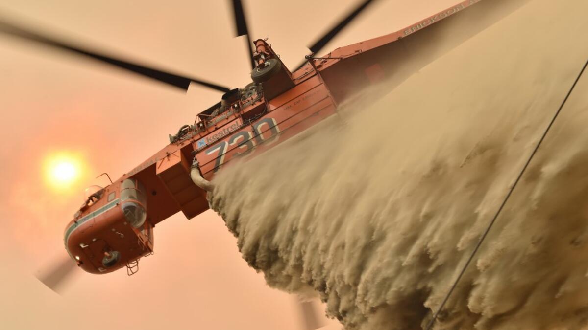 A helicopter drops fire retardent to protect a property in Balmoral, 150 kilometres southwest of Sydney on December 19, 2019. A state of emergency was declared in Australia's most populated region on December 19, as a record heat wave fanned unprecedented bushfires. PETER PARKS / AFP