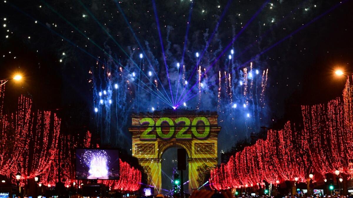 People take pictures of the fireworks erupting in the sky over the Arc de Triomphe during the New Year's celebrations on the Champs Elysees avenue, in Paris, on on January 1, 2020. Martin BUREAU / AFP