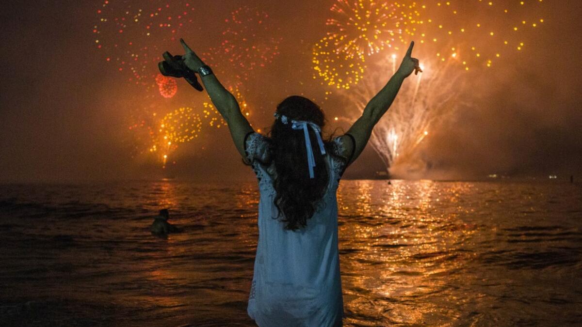 A woman celebrates as she watches the traditional New Year's fireworks at Copacabana Beach in Rio de Janeiro, Brazil, on December 31, 2019. DANIEL RAMALHO / AFP