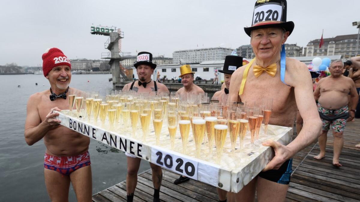 Participants celebrate during a New Year's traditional bathe at Lake Geneva in Geneva on January 1, 2020, where some 70 swimmers braved the 7degree celsius waters of the lake to take part in the event. FABRICE COFFRINI / AFP