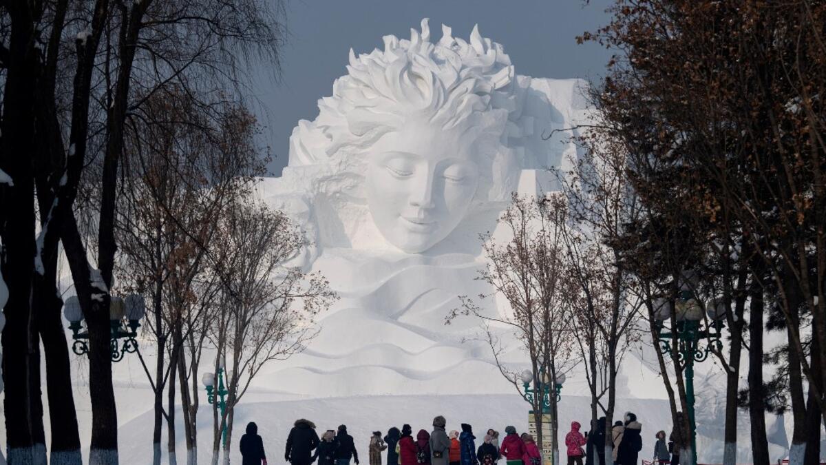 Tourists walk in front of an ice sculpture ahead of the opening of the Harbin International Ice and Snow Festival in Harbin, in China's northeast Heilongjiang province on January 4, 2020. NOEL CELIS / AFP