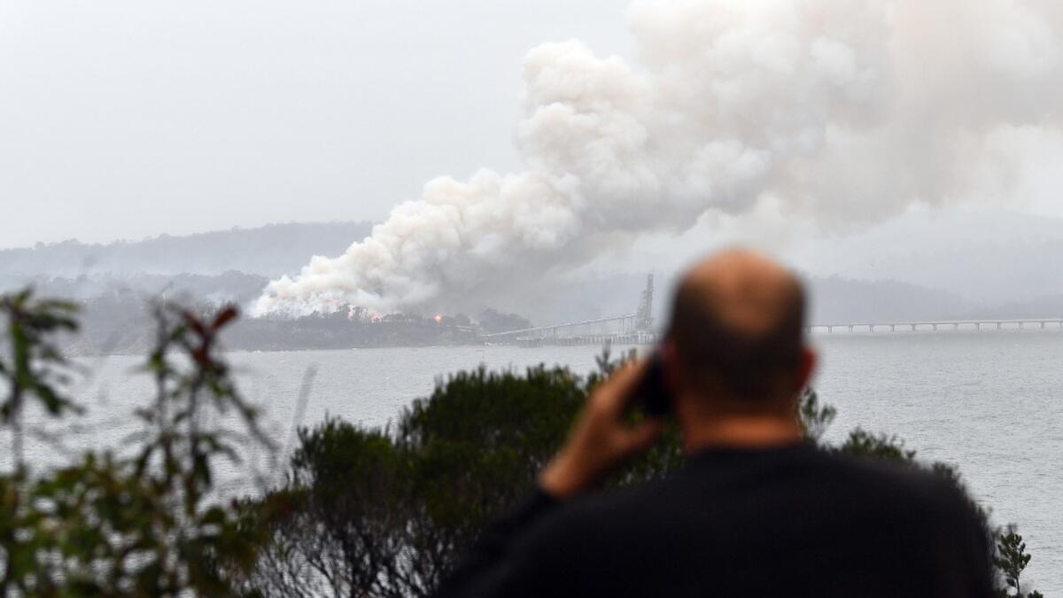 Smoke raises to the sky as a woodchip mill burns in Eden, in Australia's New South Wales state on January 6, 2020. January 5 brought milder conditions, including some rainfall in New South Wales and neighbouring Victoria state, but some communities were still under threat from out-of-control blazes, particularly in and around the town of Eden in New South Wales near the Victorian border. SAEED KHAN / AFP