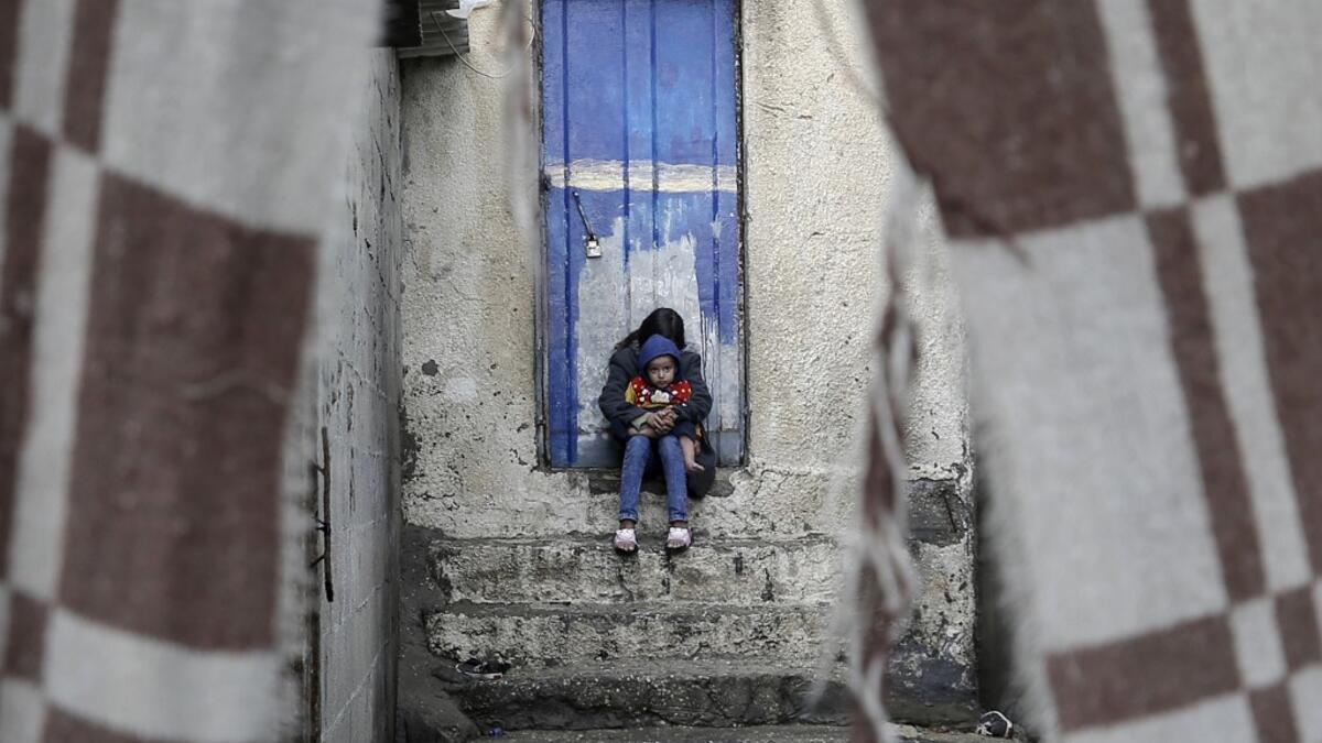 A Palestinian girl hugs her brother next to their family house during a cold weather spell in Gaza City's al-Shati camp on January 9, 2020. MOHAMMED ABED / AFP