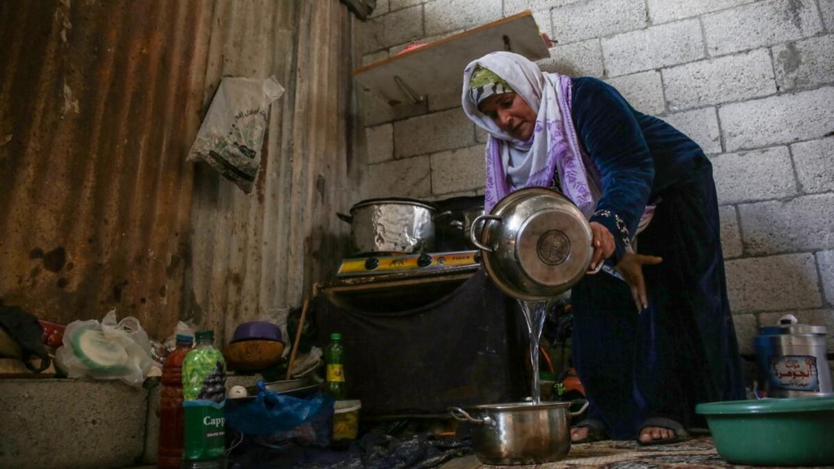 The wife of Palestinian Hammouda Abu Amra, Naama, prepares food in a shack in Khan Yunis in the southern Gaza Strip on January 10, 2020. Abu Amra, whose house was destroyed by an Israeli air strike last November, now lives in a shack with his family of seventeen. SAID KHATIB / AFP