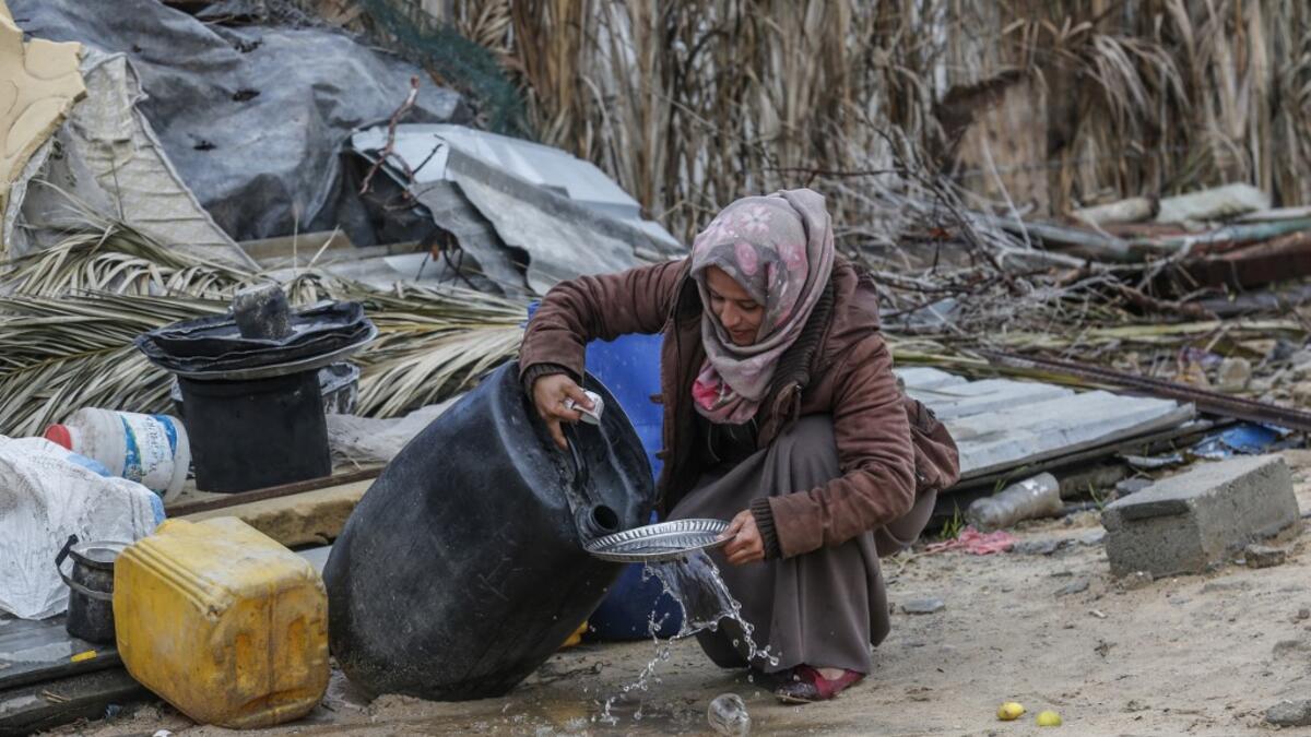 A Palestinian woman carries washes the dishes outside her shack in Khan Yunis in the southern Gaza Strip on January 10, 2020. A family of 17, whose house was destroyed by an Israeli air strike last November, now live in a shack in cold weather and heavy rain. SAID KHATIB / AFP