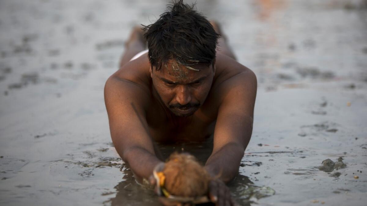 A Hindu devotee performs a ritual before taking a holy dip in the Bay of Bengal during the Gangasagar Mela, at Sagar Island, around 150 kms south of Kolkata on January 13, 2020. XAVIER GALIANA / AFP