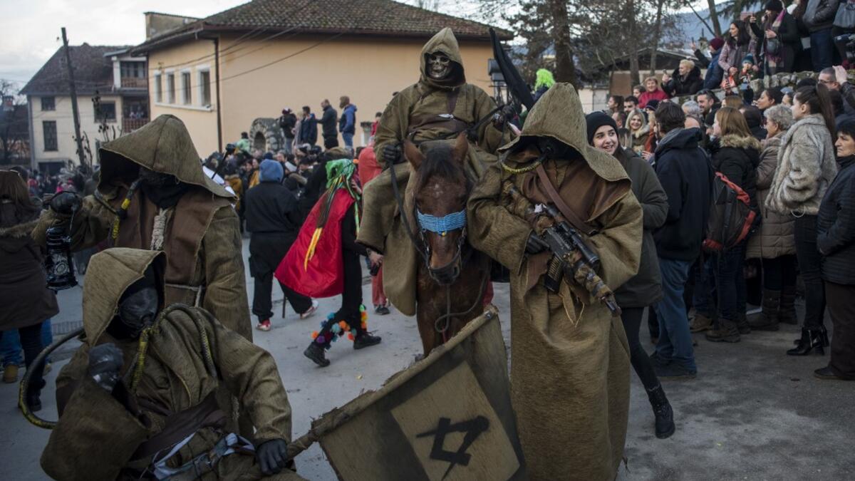 Costumed revellers sporting in their costumes a Freemason's square and compass flag and an assault rifle take part in a carnival procession through the south-western North Macedonian village of Vevcani, on January 13, 2020. The Vevcani carnival is 1,400 years old and is held every year on the eve of the feast of Saint Basil (January 14), which also marks the beginning of the New Year according to the Julian calendar, observed by the Macedonian Orthodox Church. Robert ATANASOVSKI / AFP