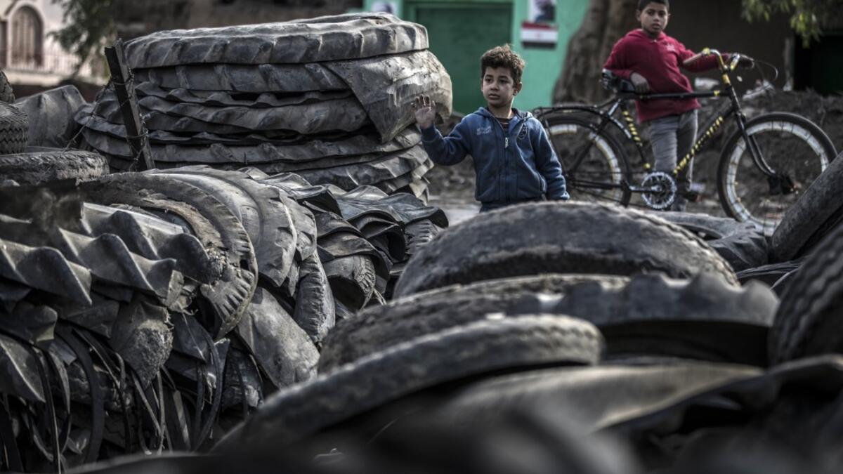 Children stand before piles of tyres at a rubber recycling workshop in the village of Mit al-Harun in Egypt's central Nile delta Gharbia Governorate, about 70 kilometres (43 miles) north of the capital, on January 14, 2020. Khaled DESOUKI / AFP