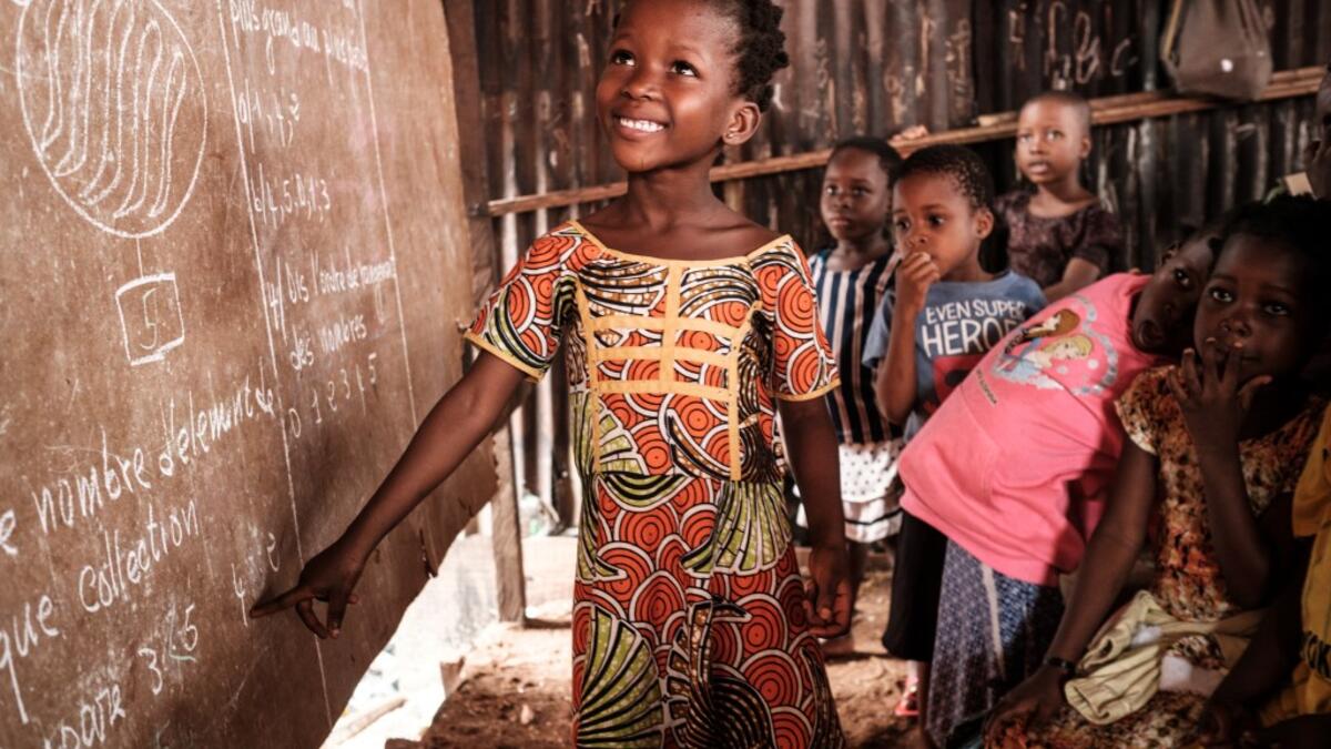 A picture taken on March 1, 2019 shows a student next to a board at a private school in the Makoko waterfront community in a polluted lagoon in Lagos, Africa’s biggest megalopolis in Nigeria. The sprawling community began in the 19th century as a fishing village for immigrants who settled on the water's edge. As more arrived and land became rare, people started to move out onto the water. Over time, Makoko became a floating realm of perhaps a quarter of a million people, although the real number is anyone's