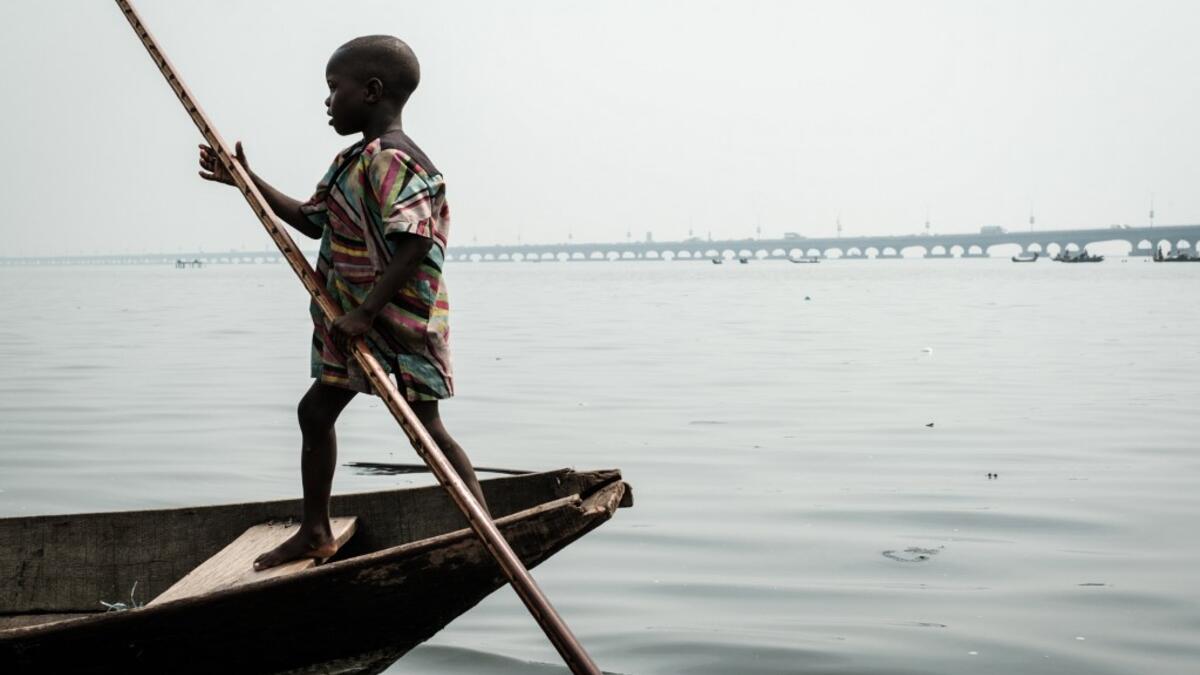 A picture taken on March 2, 2019 shows a boy steering a boat in the Makoko waterfront community in a polluted lagoon in Lagos, Africa’s biggest megalopolis in Nigeria. The sprawling community began in the 19th century as a fishing village for immigrants who settled on the water's edge. As more arrived and land became rare, people started to move out onto the water. Over time, Makoko became a floating realm of perhaps a quarter of a million people, although the real number is anyone's guess. YASUYOSHI CHIBA