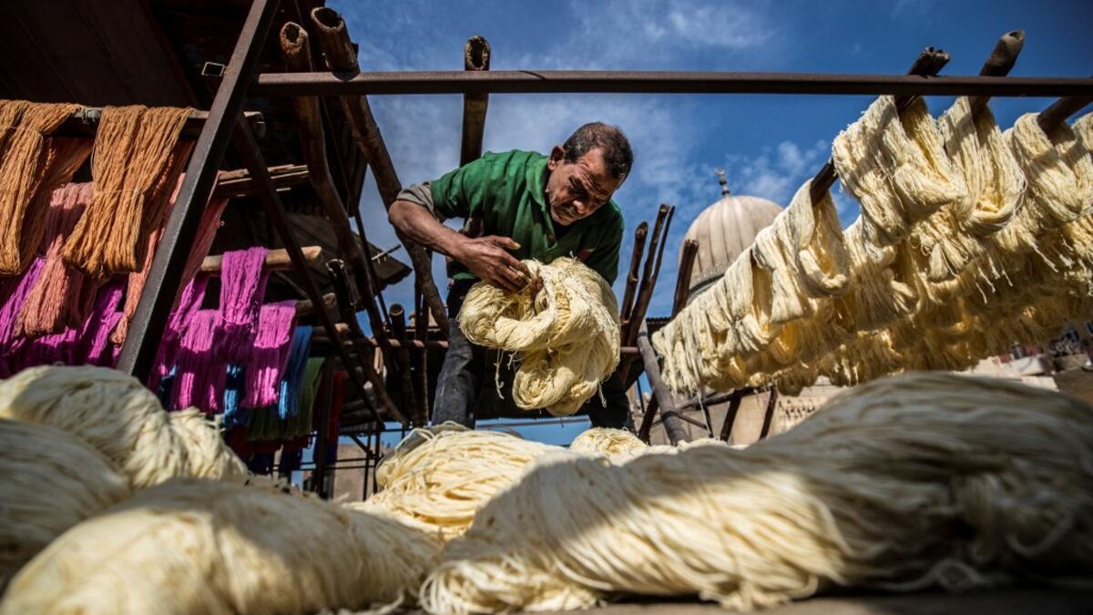 Mohamed Kamal, a 59-year-old dye worker, prepares to hang dyed yarns out to dry in the sun at a traditional hand-dying workshop in the Egyptian capital Cairo's centuries old district of Darb al-Ahmar on January 21, 2020. In Cairo's centuries-old Darb al-Ahmar district, Salama Mahmoud Salama's dye workshop is a multi-coloured den of textiles and busy workers colouring all kinds of fabrics. Khaled DESOUKI / AFP