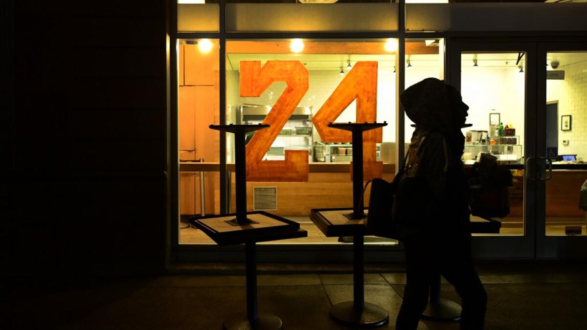 A person walks past a restaurant with "24" painted on the window as people mourn the death of NBA legend Kobe Bryant, who was killed along with his daughter and seven others in a helicopter crash on January 26, in Los Angeles on January 27, 2020. Federal investigators sifted through the wreckage of the helicopter crash that killed basketball legend Kobe Bryant and eight other people, hoping to find clues to what caused the accident that stunned the world. Frederic J. BROWN / AFP