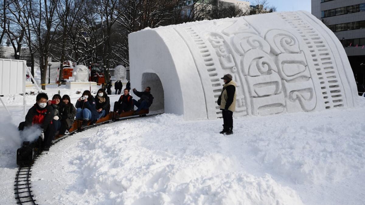 People ride a mini steam locomotive through the "Cup Noodles and Rui Hachimura's snow tunnel" during the Sapporo Snow Festival on February 4, 2020. The snow festival, which opened January 31 in the capital of Hokkaido in northern Japan, is a major draw for the region, attracting more than 2.7 million visitors last year. Organisers for this year's festival were forced to truck in an unprecedented amount of extra powder to build their signature sculptures after an unseasonably warm winter.  CHARLY TRIBALLEAU