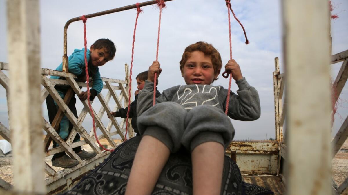 A child sits in a make-shift swing in the back of a truck in the vicinity of the northern Syrian town of Tal Abyad on February 4, 2020, where many families from the south of Aleppo province have fled to following Syrian government forces' bombardment. Bakr ALKASEM / AFP