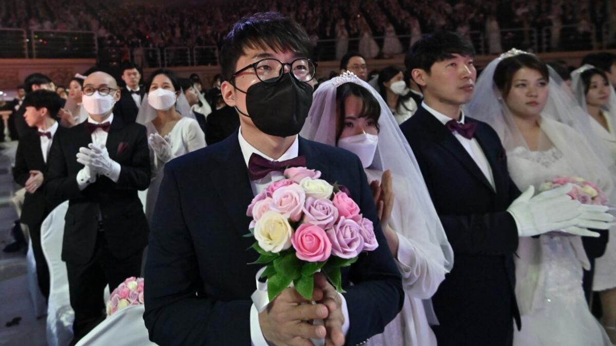 A couple wearing protective face masks attend a mass wedding ceremony organised by the Unification Church at Cheongshim Peace World Center in Gapyeong on February 7, 2020. South Korea has confirmed 24 cases of the SARS-like virus so far and placed nearly 260 people in quarantine for detailed checks amid growing public alarm. Jung Yeon-je / AFP