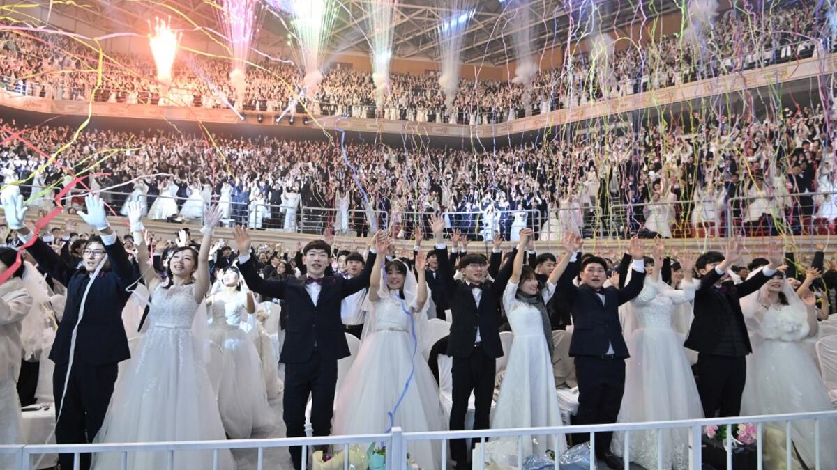 Couples cheer during a mass wedding ceremony organised by the Unification Church at Cheongshim Peace World Center in Gapyeong on February 7, 2020. Thousands of Unification Church couples married at a mass wedding to mark the eighth anniversary of the death of founder and self-proclaimed messiah Sun Myung Moon. Jung Yeon-je / AFP