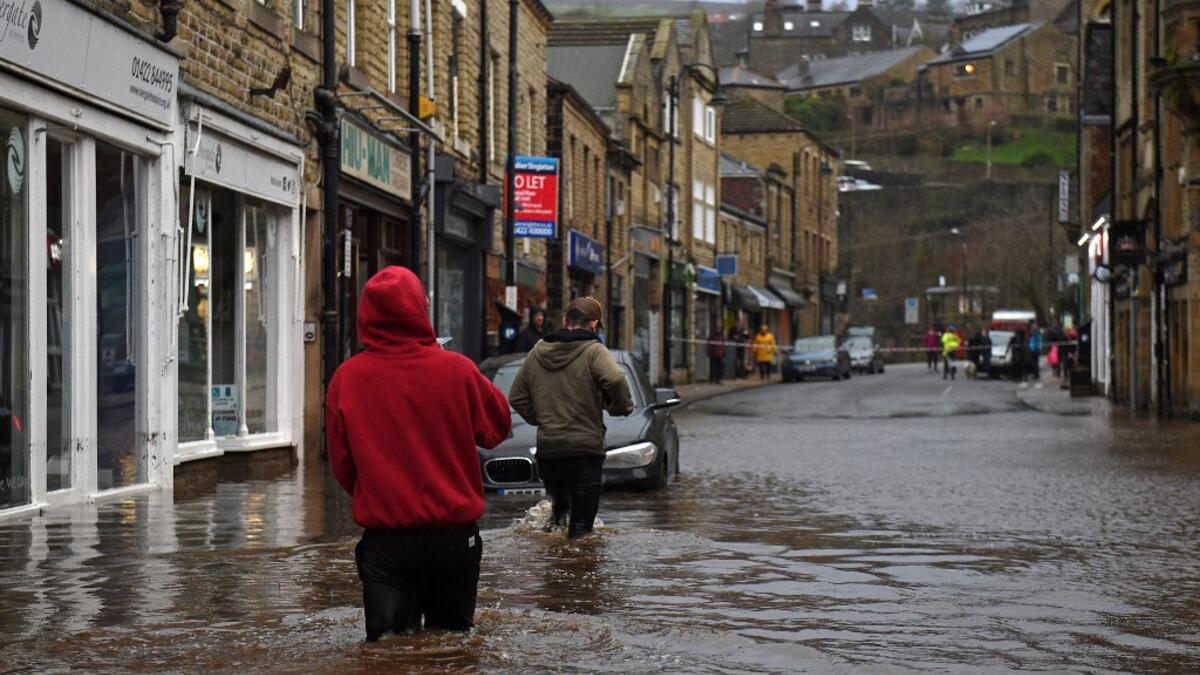 People wade through floodwater in the streets of Hebden Bridge, northern England, on February 9, 2020, as Storm Ciara swept over the country. Britain and Ireland hunkered down Sunday for a powerful storm expected to disrupt air, rail and sea links, cancel sports events, cut electrical power and damage property. With howling winds and driving rain, forecasters said Ciara would also hit France, Belgium, the Netherlands, Switzerland and Germany. Oli SCARFF / AFP