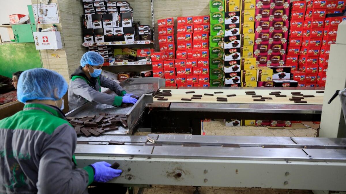 Workers at the al-Arees sweets factory sort a batch of chocolate-covered biscuits in Gaza City on February 5, 2020. Al-Arees's products are Gazan but their components are not, as few of the basic raw ingredients are produced in the impoverished Mediterranean coastal strip. Emmanuel DUNAND / AFP