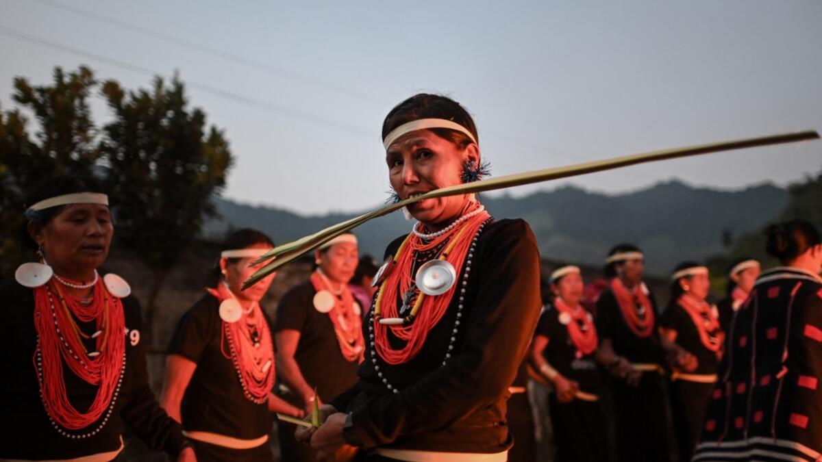 This photo taken on February 7, 2020 shows a Naga tribeswoman biting a coconut leaf at the end of an overnight ceremony to bless the harvest in Satpalaw Shaung village, Lahe township in Myanmar's Sagaing region. A haunting refrain pierces the night as the tribeswomen of the Gongwang Bonyo, among the most isolated people in Myanmar, dance around a campfire to bless the harvest ahead. Ye Aung THU / AFP