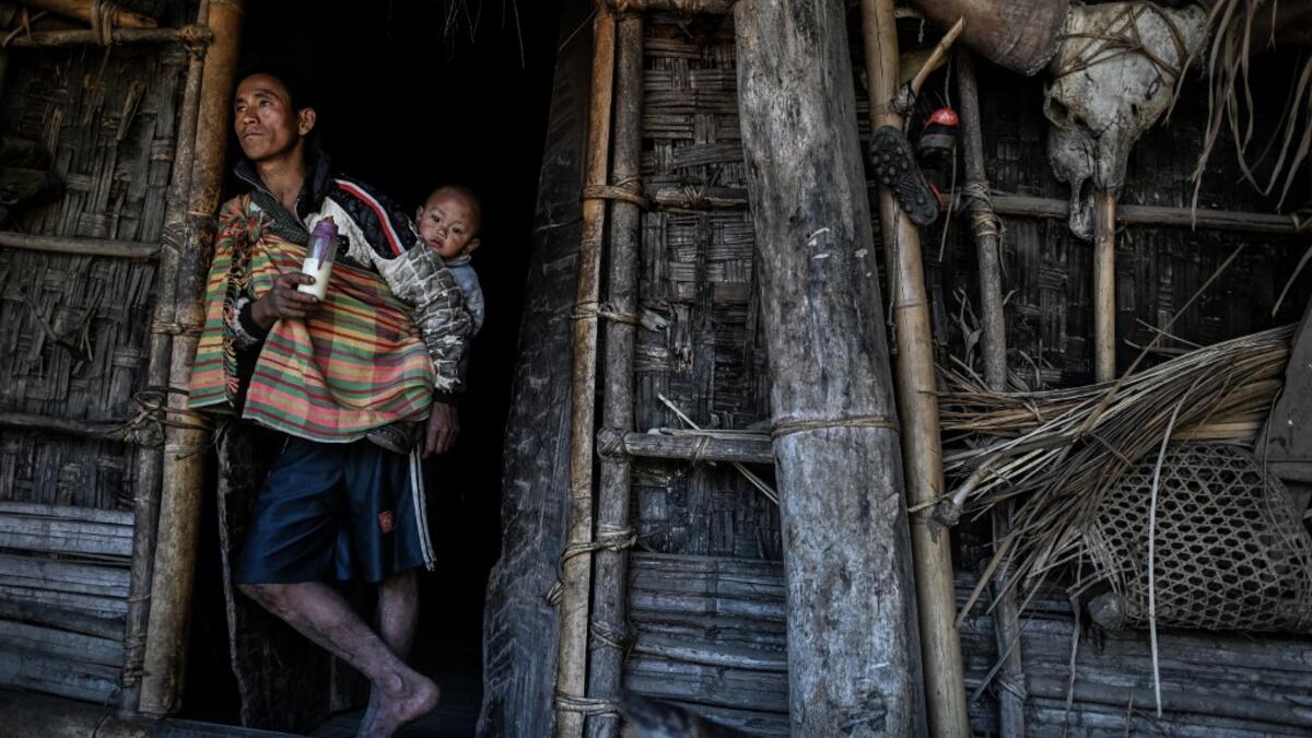 This photo taken on February 5, 2020 shows a man babysitting as his wife carries wood for the upcoming overnight ceremony by Naga tribeswomen to bless the harvest in Satpalaw Shaung village, Lahe township in Myanmar's Sagaing region. A haunting refrain pierces the night as the tribeswomen of the Gongwang Bonyo, among the most isolated people in Myanmar, dance around a campfire to bless the harvest ahead. Ye Aung THU / AFP