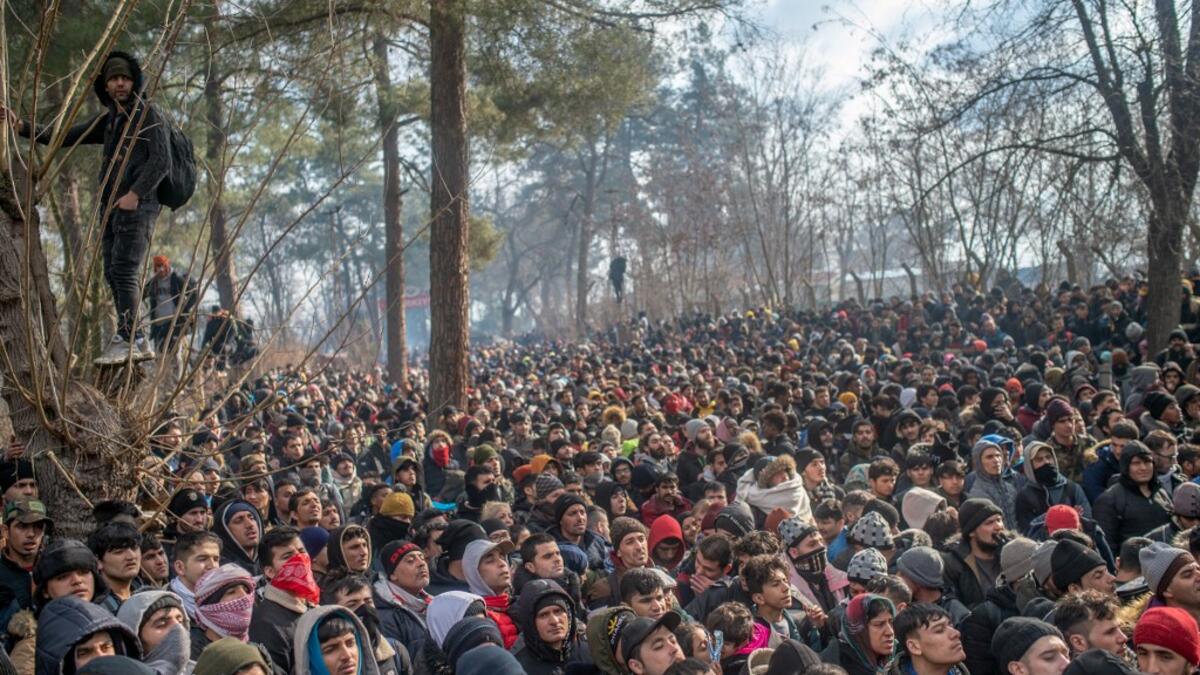 Migrants watch Greek police during clashes as they gather at the buffer zone Turkey-Greece border, at Pazarkule, in Edirne district, on February 29, 2020. Thousands of migrants stuck on the Turkey-Greece border clashed with Greek police on February 29, 2020, according to an AFP photographer at the scene. BULENT KILIC / AFP