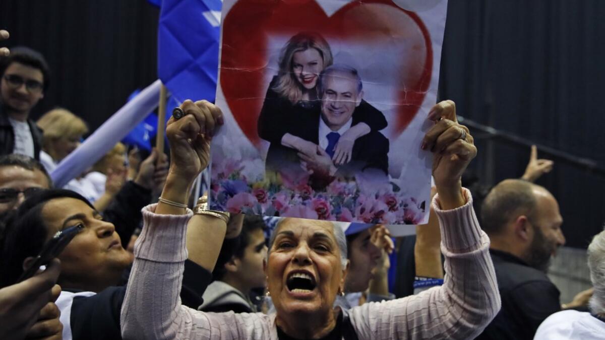 A Likud party supporter holds up a poster showing Israeli Prime Minister Benjamin Netanyahu embraced by his wife Sara with a heart behind them as she chants slogans at the Likud's electoral headquarters in the coastal city of Tel Aviv on March 2, 2020, after polls officially closed. Netanyahu claimed "a giant victory" in elections on March 3, boasting that his right-wing Likud party had defied "all expectations" in the country's third vote in less than a year. After exit polls by three networks forecast tha