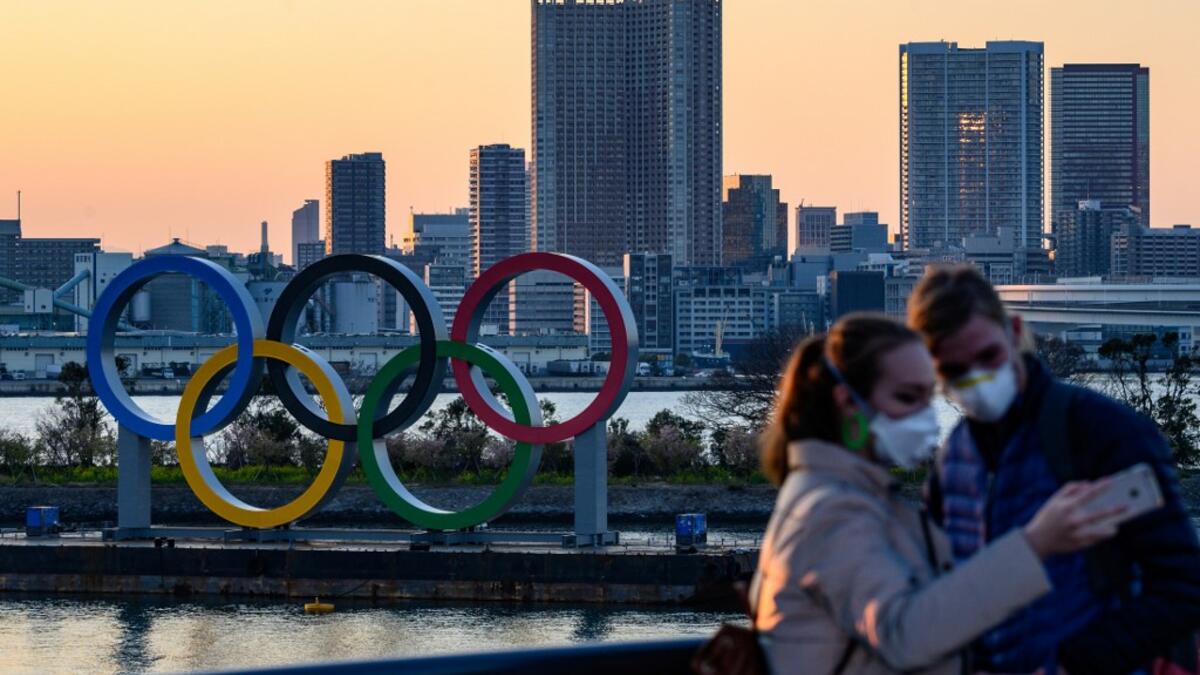 People wear face masks as they take pictures in front of the Olympic Rings at the Odaiba Seaside Park in Tokyo on March 6, 2020. Construction of all new permanent venues for the Tokyo 2020 Olympics and Paralympics is now complete, organisers said on March 6, as preparations continue despite worries over the new coronavirus outbreak. Philip FONG / AFP